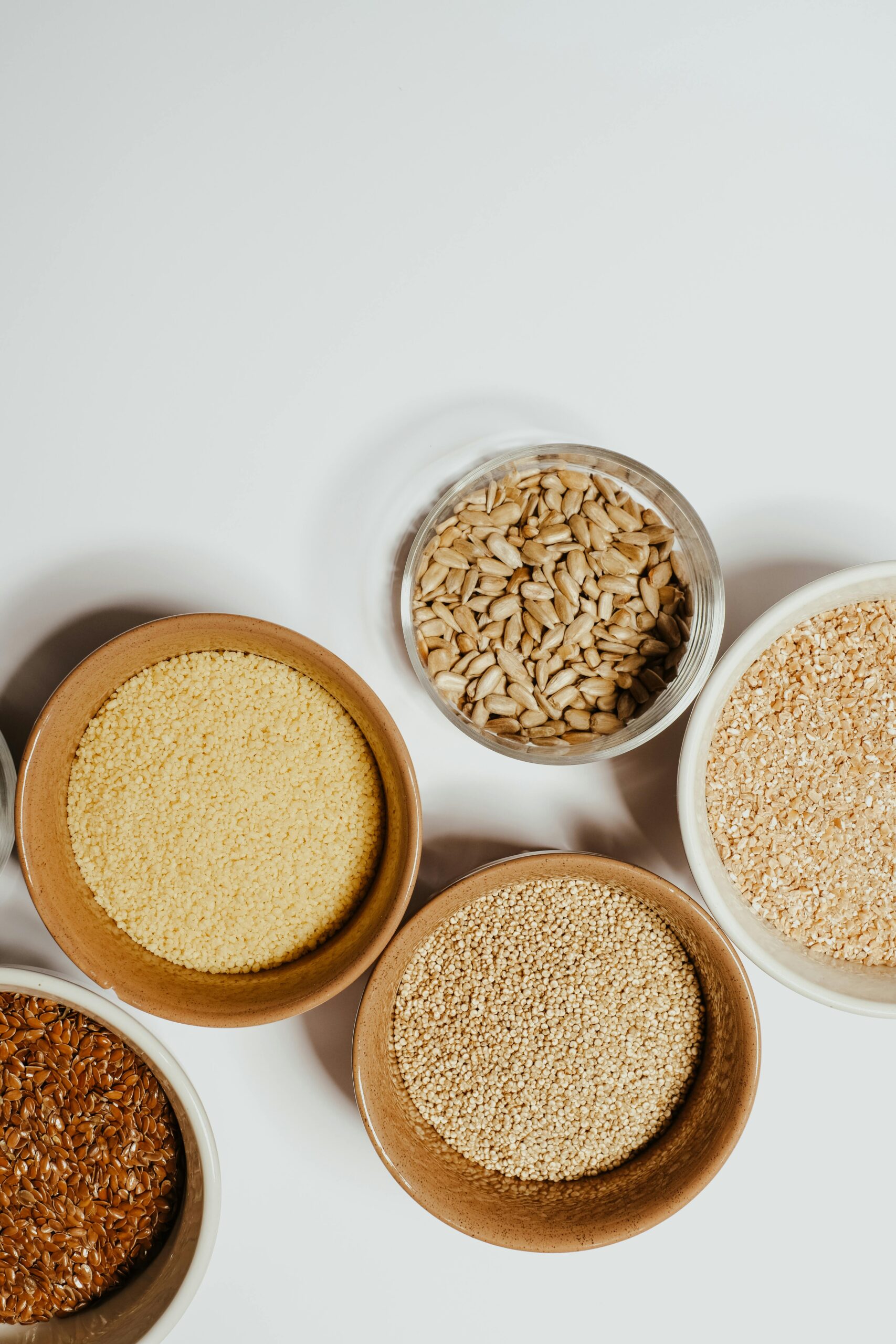 Aerial view of assorted healthy grains and seeds in bowls, highlighting nutrition and simplicity.